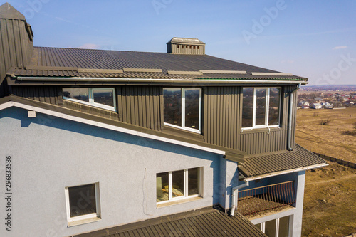Aerial view of attic annex room exterior with plastic windows, roof and walls covered with brown metal decorative siding planks, new gutter system on top of apartment building. photo