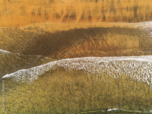 Aerial view, Wave hits sandy yellow beach. Nature background.