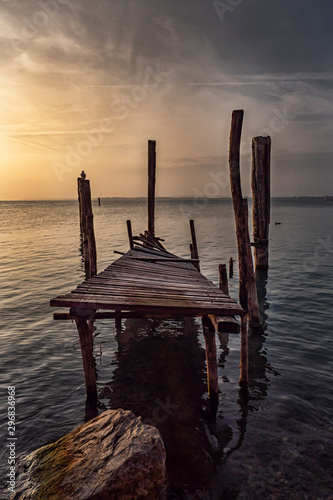 Old ruined pier on Lake Garda at sunset