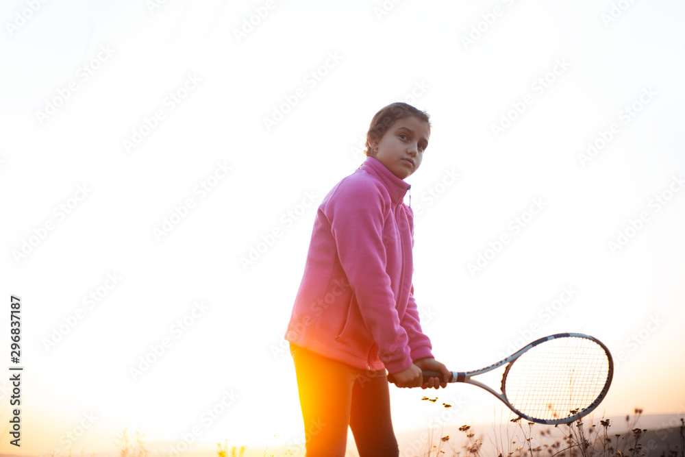 Portrait of teenage girl serving with tennis racket in hands, on white background. Wearing pink sweater. Portrait of teenage girl serving with tennis racket in hands, on white background. Wearing pink sweater.