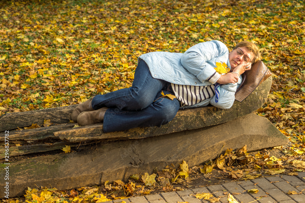 Happy Mature woman in glasses and blue scarf resting in the city Park Happy Mature woman in glasses and blue scarf resting in the city Park