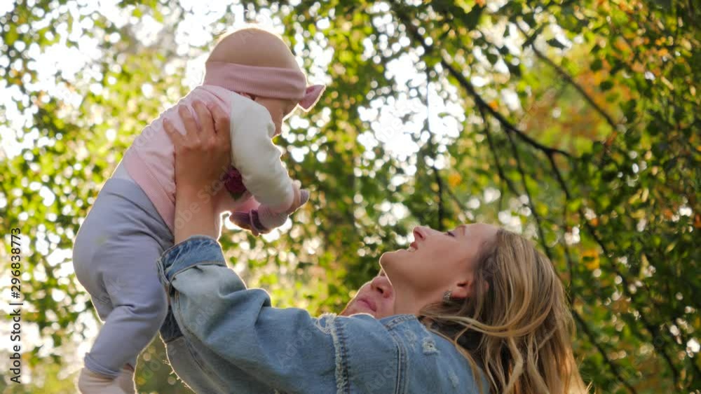 Happy young parents mother and father take their baby child from a rug toss it up hugging and kissing Happy young parents mother and father take their baby child from a rug toss it up hugging and kissing