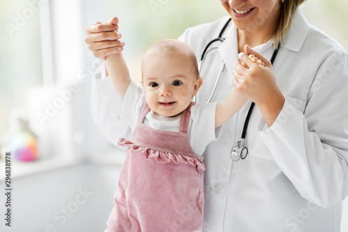 medicine, healthcare and pediatrics concept - female pediatrician or neuropathist doctor or nurse checking smiling baby girl patient's health at clinic or hospital