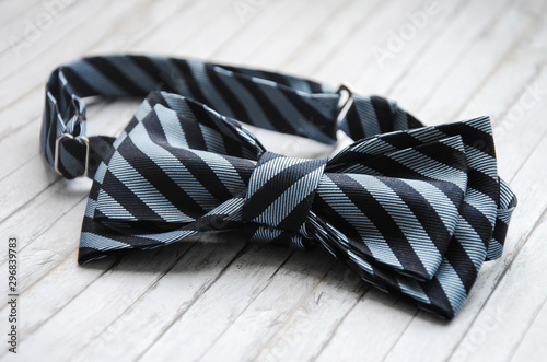 Striped blue bowtie on a wooden background. Accessory for formal dress. Symbol of elegance and fashion for men. Men's casual. Men's and women's accessories. Men's and women's bow tie.