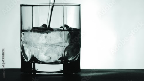 Pouring mineral water with ice in the glass.