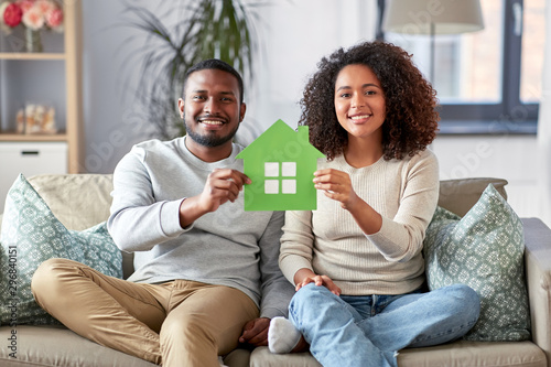 relations and people concept - happy african american couple sitting on sofa at home