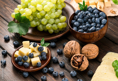 .cheese grapes and blueberries on a wooden background
