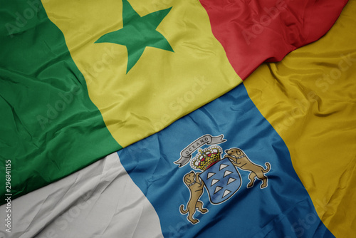 waving colorful flag of canary islands and national flag of senegal.