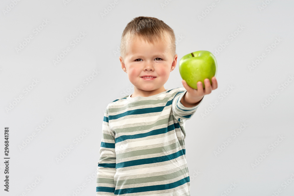 education, health and childhood concept - portrait of smiling little boy holding green apple over grey background education, health and childhood concept - portrait of smiling little boy holding green apple over grey background