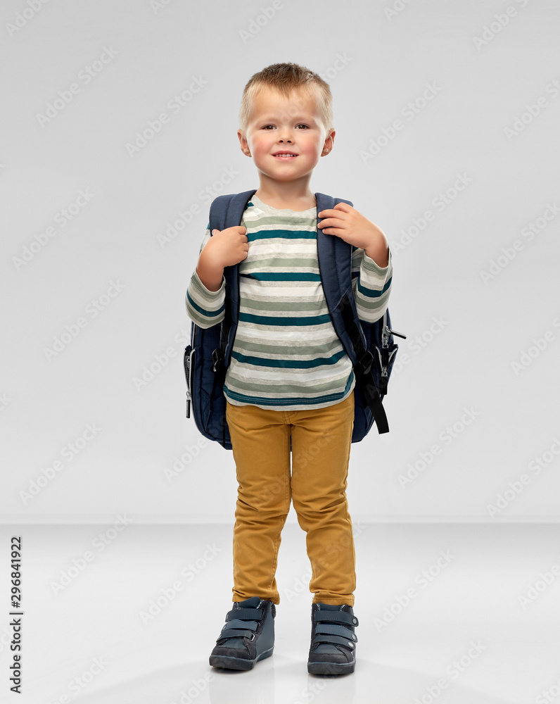 preschool education and childhood concept - portrait of smiling little boy with school backpack over grey background preschool education and childhood concept - portrait of smiling little boy with school backpack over grey background