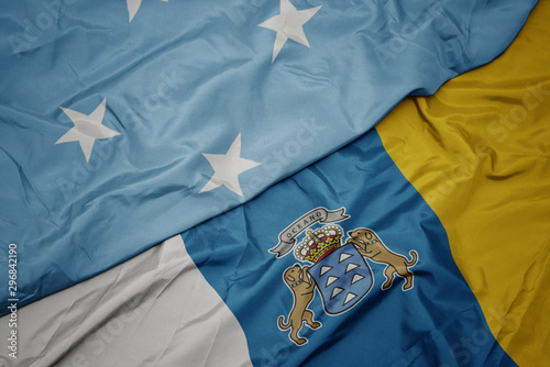 waving colorful flag of canary islands and national flag of Federated States of Micronesia .
