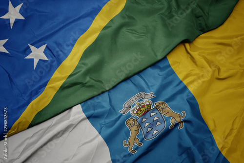 waving colorful flag of canary islands and national flag of Solomon Islands .