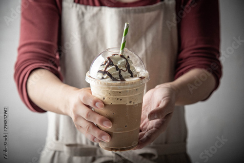 barista serving coffee frappuccino in plastic cup photo