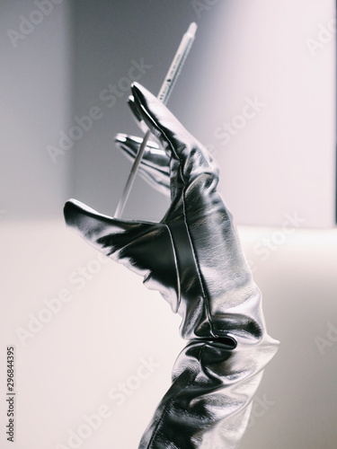 Silver gloved hand holding syringe photo