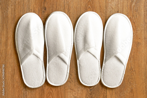 Top view two pairs of new soft white slipper in the hotel on wooden floor. Four white slipper, Isolated on wooden floor. Top view.