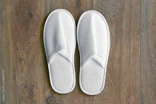 Top view of a pair of new soft white slippers in the hotel on wooden floor. A pair white slippers, Isolated on wooden floor. Top view. 