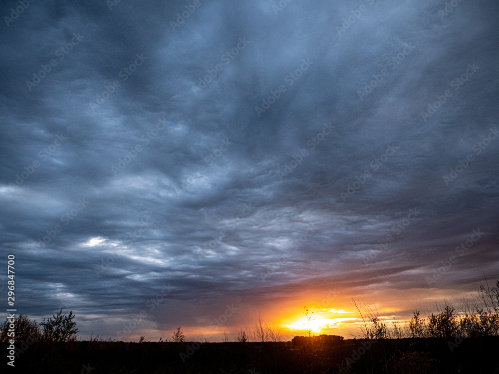Sunset trough gray clouds on an autumn evening