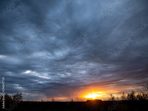 Sunset trough gray clouds on an autumn evening