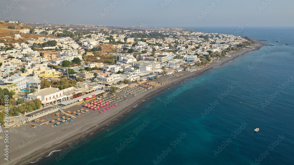 Aerial drone photo of famous seaside village and organised with sun-beds and umbrellas sandy beach of Kamari, Santorini island, Cyclades, Greece