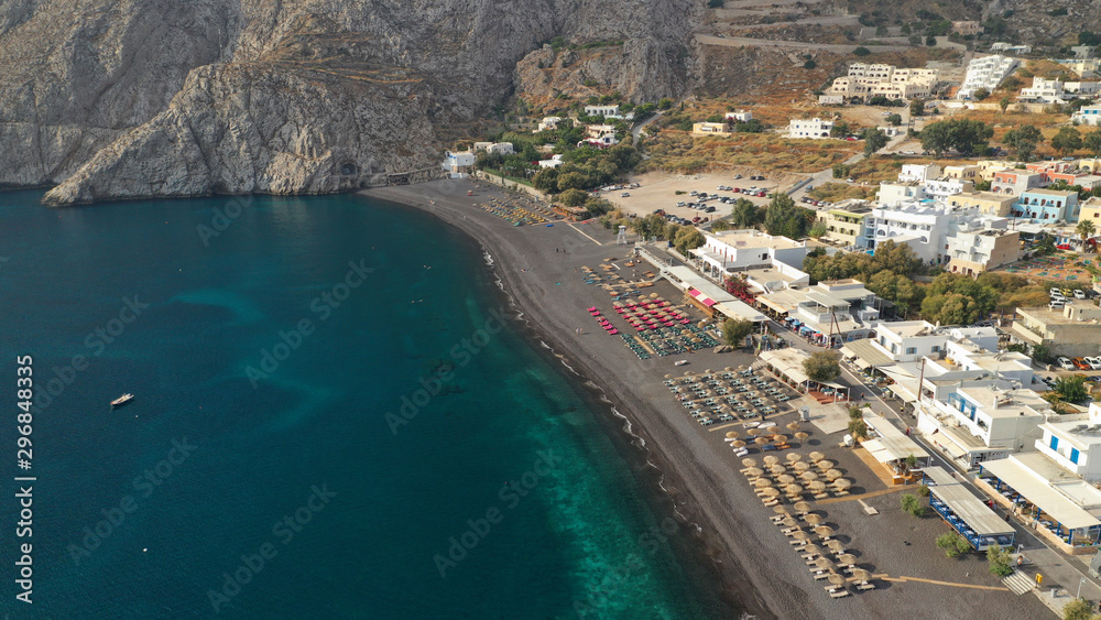 Aerial drone photo of famous seaside village and organised with sun-beds and umbrellas sandy beach of Kamari, Santorini island, Cyclades, Greece