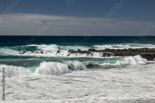 Steep high lava rock cliffs. Blue sea horizon  natural sky background.