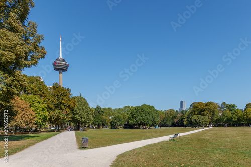 Fototapeta Naklejka Na Ścianę i Meble -  Outdoor sunny view of Innerer Grüngürtel, park in city center, with background of Colonius Broadcasting Tower against blue sky in Cologne, Germany.