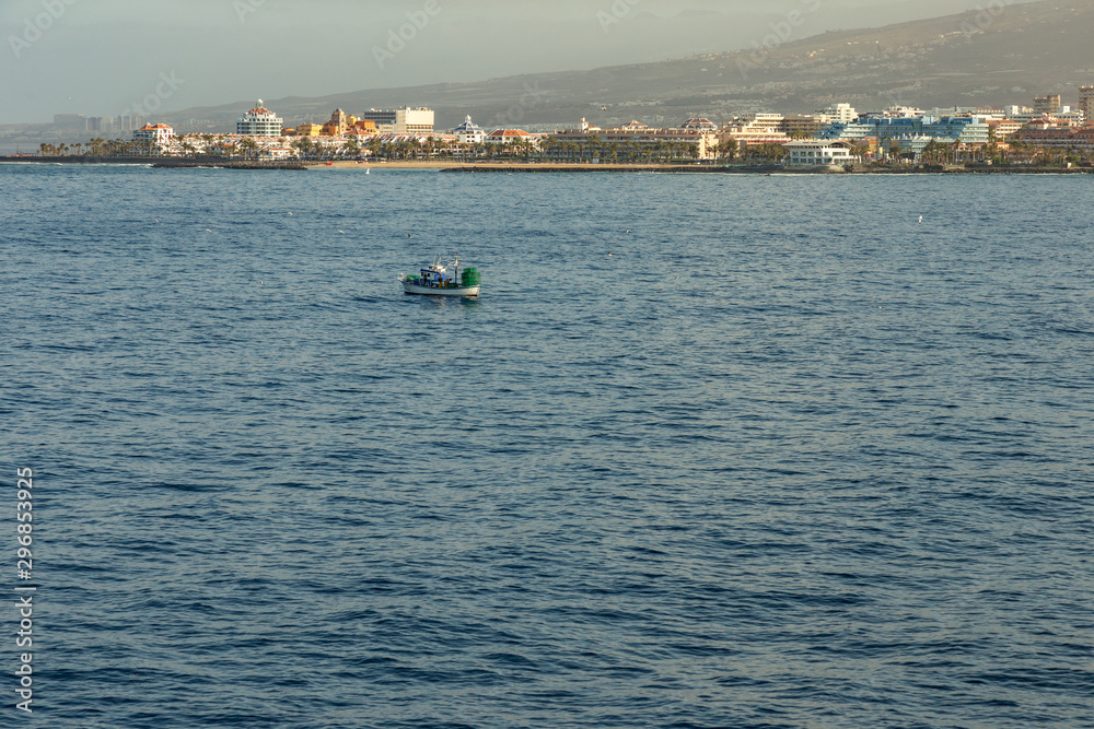 Las Americas, Tenerife, Spain - May 25, 2019: View to the coastline and small fishing boat from the ferry departing for the island of La Gomera early morning from the port of Los Cristianos