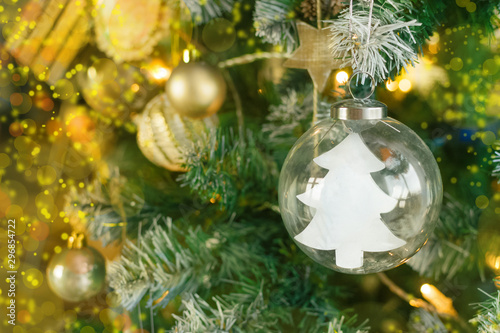 Decorative Christmas tree on a light background with shiny balls and a glass ball inside which is a Christmas tree with copyspace