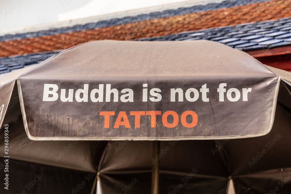 Obraz premium Bangkok city, Thailand - March 17, 2019: Tattoo statement of Buddha printed on patio umbrella at Temple of Dawn, with black and red roof on top.