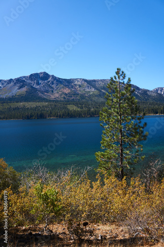 Vertical photo of mountains in the background and a mountain lake with fall colors in the foreground