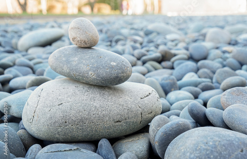 Stacked rocks or stones on a dry river bed outside in nature. Smooth pebbles with light gray tones in ambient light.