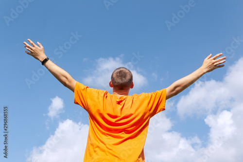 The guy stands with his arms outstretched to the sky