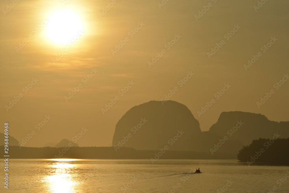 A siling fishing boat on gold sea surface in a morning