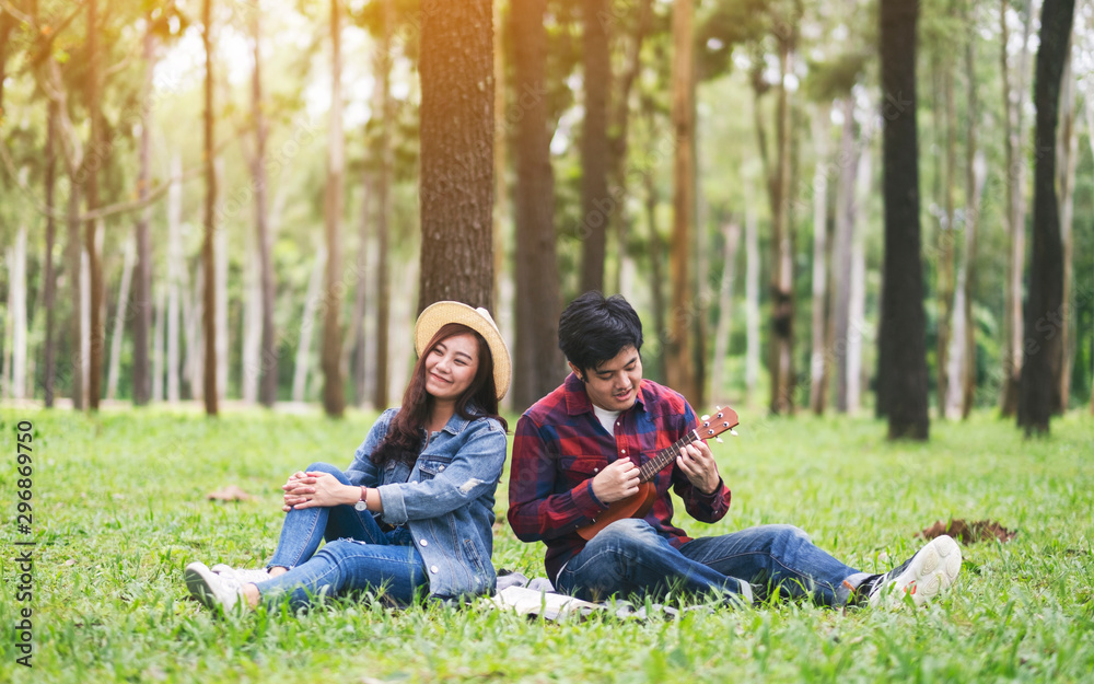 A young couple playing ukulele together in the woods