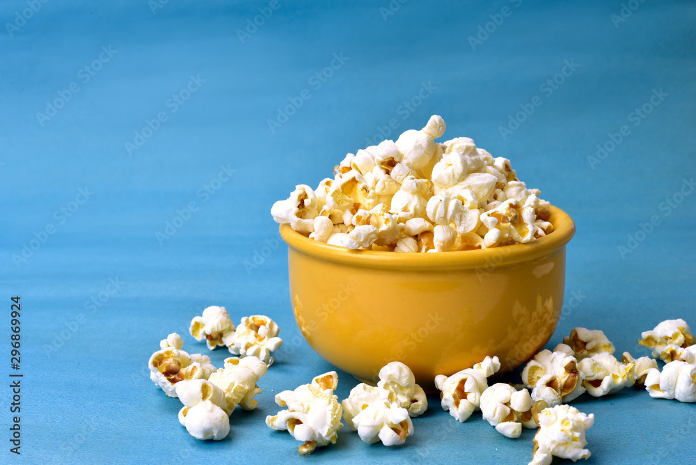 popcorn inside bowl with pink bottom with corn beside on blue background popcorn inside bowl with pink bottom with corn beside on blue background