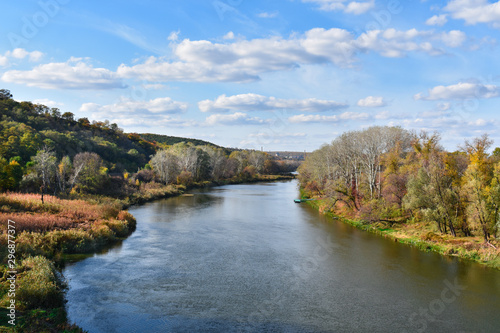 Autumn landscape with a river, trees and beautiful clouds.