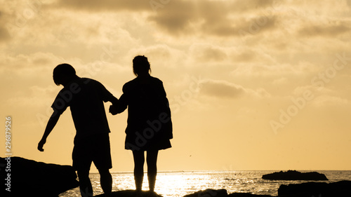 silhouettes of a couple at the beach watching sunset