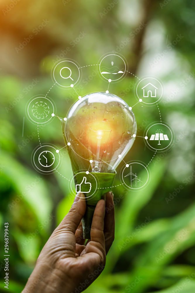 hand holding light bulb against nature, icons energy sources for ...