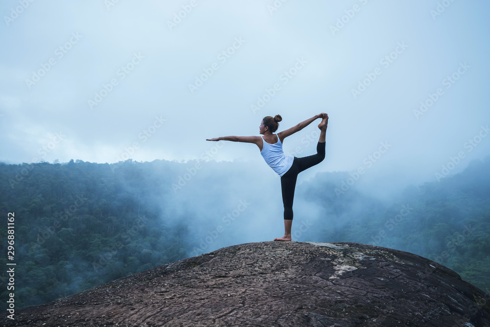 Young woman exercises yoga in the mountains. Asian woman travel nature. Travel relax exercises yoga touch natural fog on mountain peak. Young woman exercises yoga in the mountains. Asian woman travel nature. Travel relax exercises yoga touch natural fog on mountain peak.