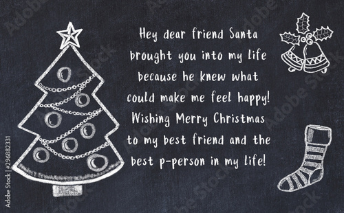 Drawing of christmas tree and handwritten greetings on black chalkboard  photo