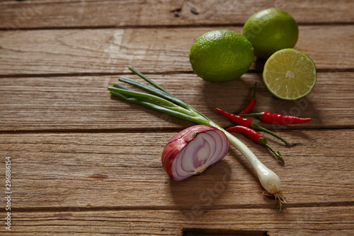 Fototapeta Naklejka Na Ścianę i Meble -  Ingredients set for Thai spicy soup (Tom-yum) include lemon, red chili ,red onion lemongrass and green lime on wood table.