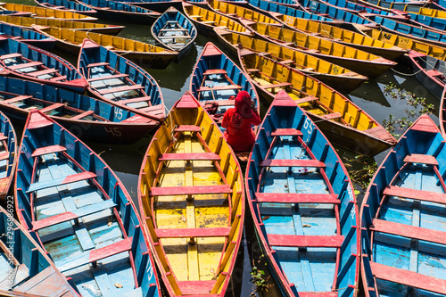 Fototapeta Naklejka Na Ścianę i Meble -  colorful boats in Fewa lake in Pokhara, Nepal with women in red sitting inside
