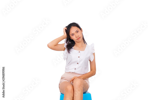 An asian girl in white sitting on blue stool and touching her own head