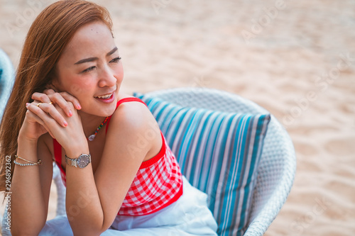 traveler girl in red dress sit on the chair in beach with vacation trip in emotional relax and smile for relax concept