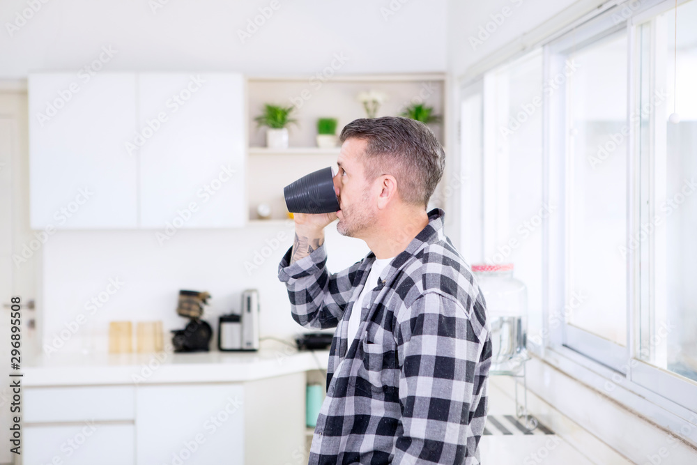 Caucasian man drinking coffee in the kitchen