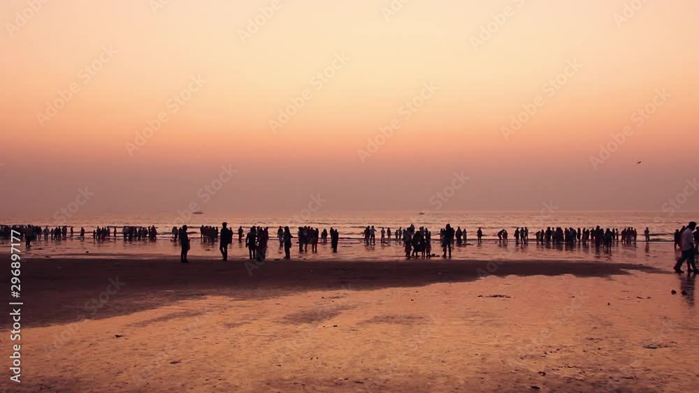 A crowd of people enjoying an orange sunset at juhu beach, Mumbai A crowd of people enjoying an orange sunset at juhu beach, Mumbai