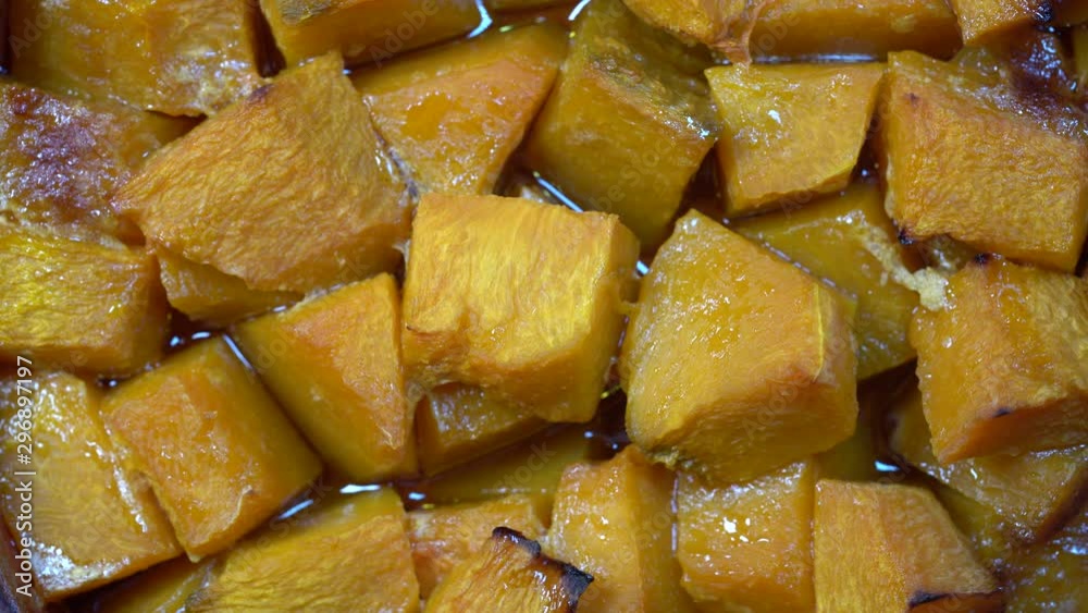 Baked yellow pumpkin with honey, olive oil and spices on a plate, rotates. Vegetarian food. Close up
