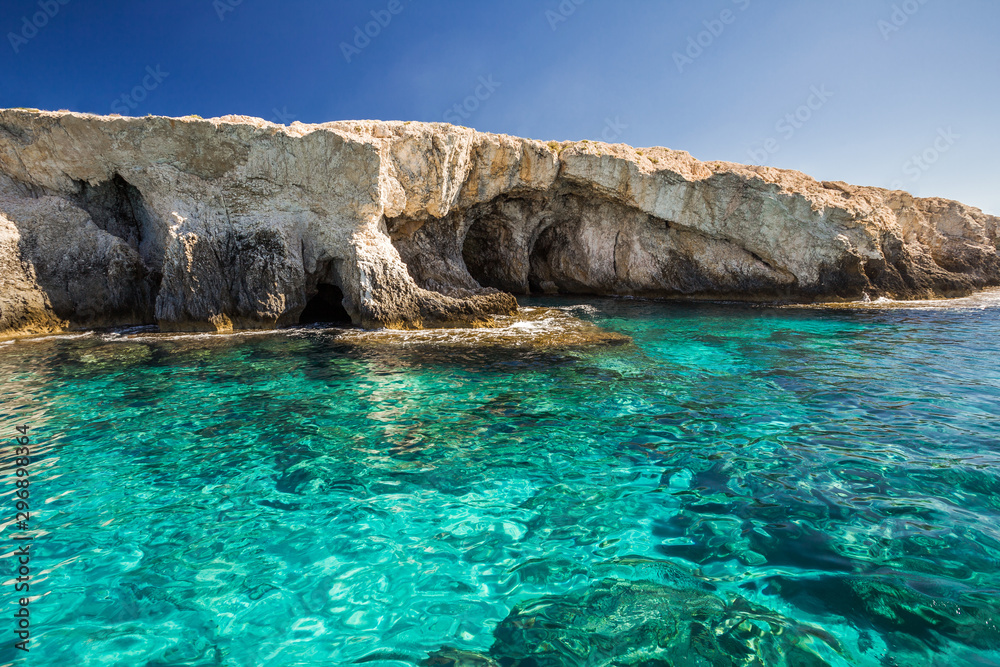 Rocky shore, clear turquoise water and blue sky.