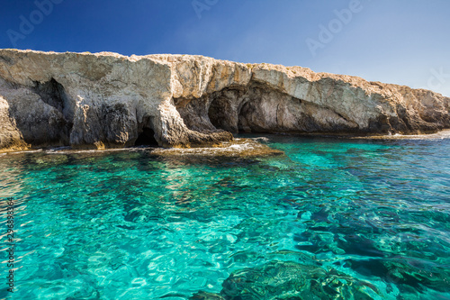 Rocky shore, clear turquoise water and blue sky.