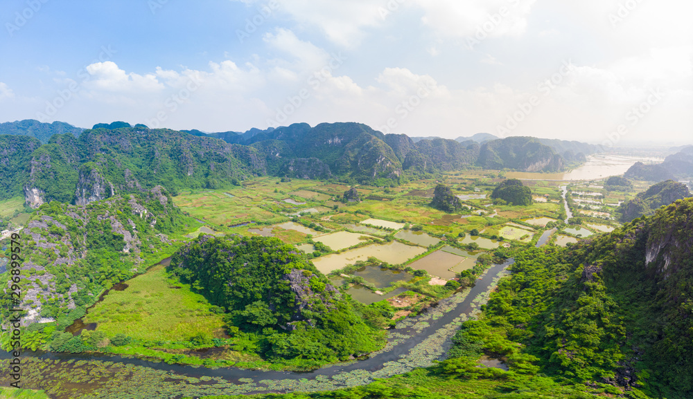 Epic aerial view of Ninh Binh region, Trang An Tam Coc tourist attraction, UNESCO World Heritage Site, Scenic river crawling through karst mountain ranges in Vietnam, travel destination.